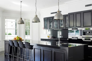 This is an example of a traditional galley kitchen in Sydney with recessed-panel cabinets, dark wood cabinets, stainless steel appliances, dark hardwood floors and with island.