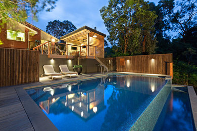 Inspiration for a mid-sized contemporary backyard rectangular infinity pool in Melbourne with a pool house and tile.