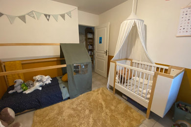 Cette photo montre une petite chambre de bébé neutre chic avec un mur orange, un sol en carrelage de porcelaine et un sol beige.