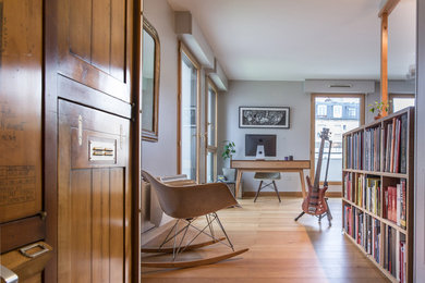 Foto de despacho contemporáneo de tamaño medio con paredes grises, suelo de madera clara, escritorio independiente y suelo marrón