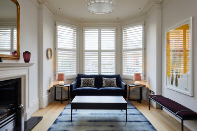 Photo of a medium sized modern enclosed living room in Surrey with white walls and light hardwood flooring.