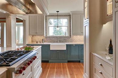 This is an example of a large l-shaped eat-in kitchen in Portland with recessed-panel cabinets, blue cabinets, quartzite benchtops, white splashback, subway tile splashback, medium hardwood floors and white benchtop.