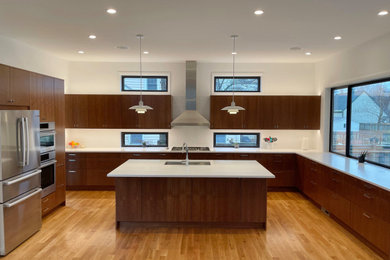 Large 1960s medium tone wood floor kitchen photo in Seattle with an undermount sink, flat-panel cabinets, medium tone wood cabinets, ceramic backsplash, stainless steel appliances, an island and white countertops