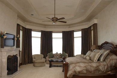 Large elegant master carpeted bedroom photo with beige walls, a standard fireplace and a stone fireplace