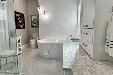 Cette photo montre une salle de bain chic avec une baignoire indépendante, un mur gris, un plan de toilette en quartz et meuble-lavabo encastré.
