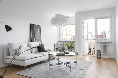 Idéer för att renovera ett skandinaviskt vardagsrum, med vita väggar, ljust trägolv och beiget golv