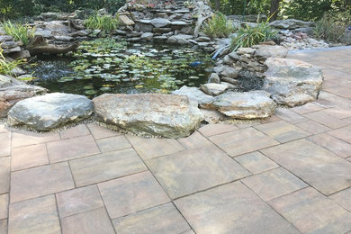 Photo of a large traditional full sun backyard stone pond in Other.