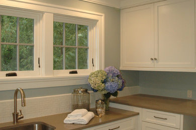 Laundry room - transitional l-shaped porcelain tile laundry room idea in Seattle with an undermount sink, flat-panel cabinets, white cabinets and blue walls
