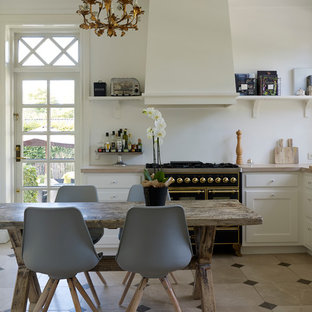 Свежая идея для дизайна: маленькая п-образная кухня в классическом стиле с накладной раковиной, белыми фасадами, белым фартуком, черной техникой, полом из известняка, обеденным столом, фасадами с утопленной филенкой и столешницей из известняка без острова - отличное фото интерьера