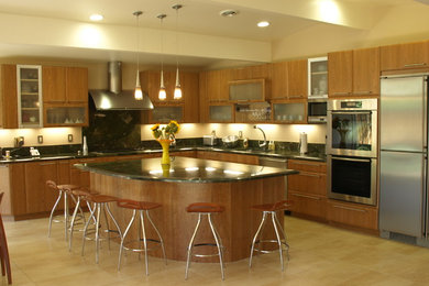 This is an example of a large contemporary l-shaped open plan kitchen in San Francisco with a single-bowl sink, flat-panel cabinets, granite benchtops, green splashback, stone slab splashback, stainless steel appliances, with island, light wood cabinets, light hardwood floors and beige floor.