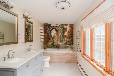 This is an example of a large transitional master bathroom in Boston with recessed-panel cabinets, beige cabinets, a drop-in tub, a double shower, a two-piece toilet, beige tile, porcelain tile, multi-coloured walls, porcelain floors, an undermount sink, engineered quartz benchtops, beige floor and beige benchtops.
