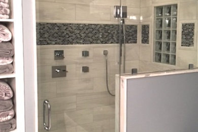 This is an example of a mid-sized transitional master bathroom in New York with raised-panel cabinets, dark wood cabinets, a freestanding tub, grey walls, marble floors, an undermount sink, quartzite benchtops, an alcove shower, gray tile, white tile, porcelain tile, a hinged shower door and grey floor.