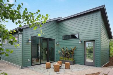 Example of a trendy green one-story exterior home design in Portland with a shingle roof