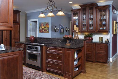 Inspiration for a large traditional l-shaped eat-in kitchen in Atlanta with an undermount sink, recessed-panel cabinets, dark wood cabinets, granite benchtops, beige splashback, stone tile splashback, stainless steel appliances, medium hardwood floors and with island.