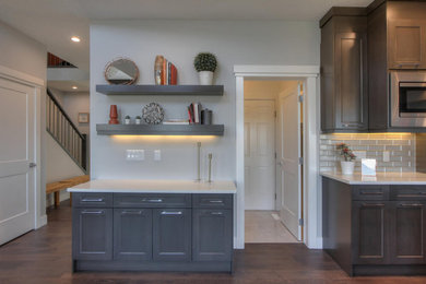 Mid-sized minimalist dark wood floor and brown floor kitchen pantry photo in Edmonton with raised-panel cabinets, dark wood cabinets, granite countertops, white backsplash, subway tile backsplash and white countertops