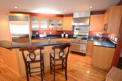 Inspiration for a mid-sized transitional u-shaped light wood floor eat-in kitchen remodel in Other with an undermount sink, shaker cabinets, light wood cabinets, quartz countertops, stainless steel appliances, an island and black countertops