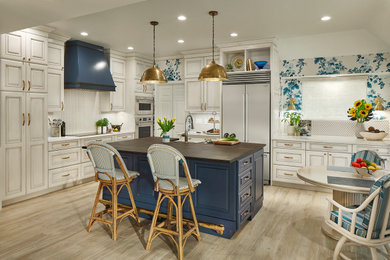 Inspiration for a beige floor kitchen remodel in Dallas with a farmhouse sink, raised-panel cabinets, white cabinets, white backsplash, stainless steel appliances, an island and white countertops
