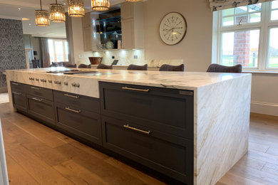 Photo of a large classic u-shaped kitchen/diner in Edinburgh with a built-in sink, shaker cabinets, blue cabinets, marble worktops, black appliances, medium hardwood flooring, an island, brown floors, multicoloured worktops, multi-coloured splashback and marble splashback.