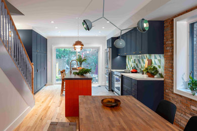 Inspiration for a contemporary medium tone wood floor and brown floor kitchen remodel in Toronto with an undermount sink, recessed-panel cabinets, blue cabinets, wood countertops, green backsplash, ceramic backsplash, stainless steel appliances, an island and white countertops
