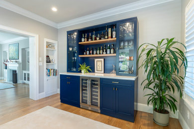 Dry bar - mid-sized contemporary single-wall medium tone wood floor dry bar idea in San Francisco with no sink, glass-front cabinets, blue cabinets, solid surface countertops, blue backsplash and white countertops