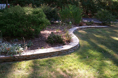 Design ideas for a mid-sized traditional shade backyard stone retaining wall landscape in Raleigh for fall.