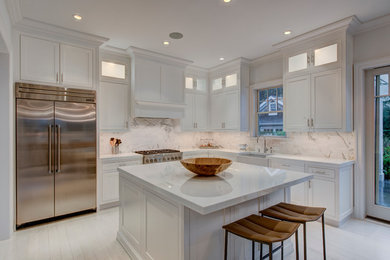 Mid-sized traditional l-shaped eat-in kitchen in New York with a farmhouse sink, recessed-panel cabinets, white cabinets, white splashback, stainless steel appliances, painted wood floors, with island, solid surface benchtops, stone tile splashback and white benchtop.