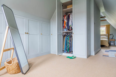 Diseño de armario vestidor unisex tradicional de tamaño medio con armarios estilo shaker, puertas de armario azules, moqueta y suelo beige