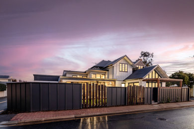 Photo of an expansive two-storey white house exterior in Adelaide with board and batten siding, a metal roof and a grey roof.
