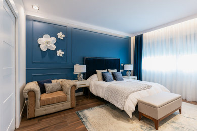 Modelo de dormitorio principal clásico renovado grande con paredes azules, suelo de baldosas de cerámica, suelo marrón y boiserie