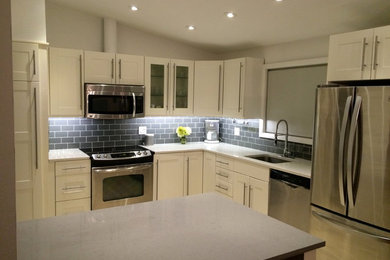 Inspiration for a mid-sized mid-century modern u-shaped porcelain tile eat-in kitchen remodel in New York with an island, shaker cabinets, white cabinets, quartz countertops, gray backsplash, glass tile backsplash, stainless steel appliances and an undermount sink