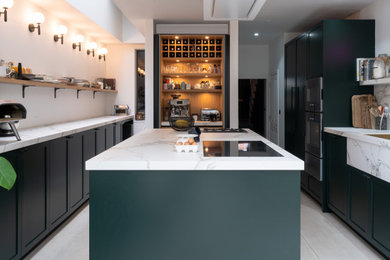 This is an example of a medium sized classic kitchen/diner in London with shaker cabinets, green cabinets, composite countertops, coloured appliances, an island and white worktops.
