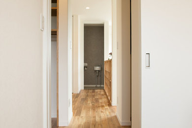 Photo of a scandinavian hallway in Other with white walls, medium hardwood floors and brown floor.