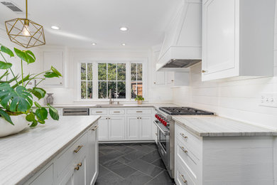 This is an example of a large contemporary l-shaped kitchen/diner in New Orleans with a submerged sink, shaker cabinets, white cabinets, quartz worktops, white splashback, slate splashback, stainless steel appliances, slate flooring, an island, black floors and multicoloured worktops.