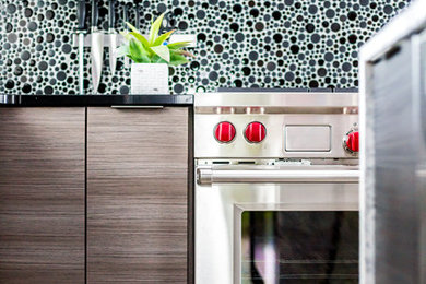 Example of a mid-sized trendy porcelain tile eat-in kitchen design in Salt Lake City with an undermount sink, flat-panel cabinets, dark wood cabinets, granite countertops, black backsplash, mosaic tile backsplash, stainless steel appliances and an island