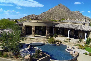 Hot tub - large modern backyard stone and custom-shaped hot tub idea in Phoenix