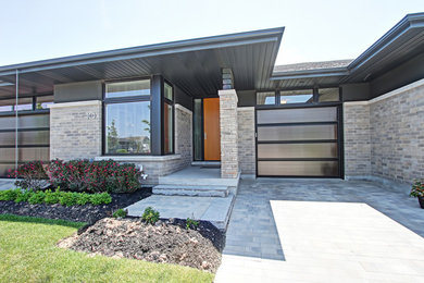 Mid-sized contemporary one-storey brick grey house exterior in Toronto with a hip roof and a shingle roof.