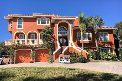 Example of a large island style two-story stucco house exterior design in Tampa with a hip roof and a tile roof