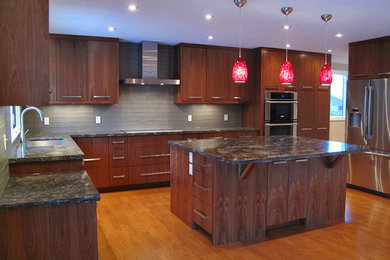 This is an example of a large contemporary u-shaped kitchen in Calgary with an undermount sink, flat-panel cabinets, dark wood cabinets, granite benchtops, grey splashback, glass tile splashback, stainless steel appliances, medium hardwood floors, with island and brown floor.