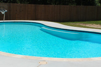 Large transitional backyard concrete and kidney-shaped natural hot tub photo in Houston