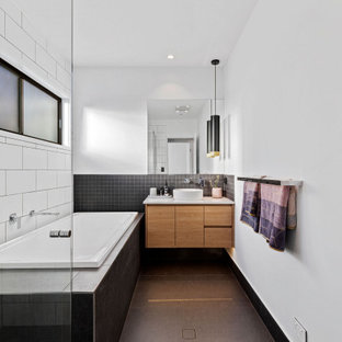 Inspiration for a contemporary bathroom in Sunshine Coast with flat-panel cabinets, medium wood cabinets, a drop-in tub, black and white tile, white walls, a vessel sink, grey floor and white benchtops.