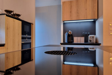 Diseño de cocina contemporánea grande abierta con fregadero bajoencimera, armarios con paneles empotrados, encimera de granito, salpicadero negro, salpicadero de madera, electrodomésticos negros y una isla