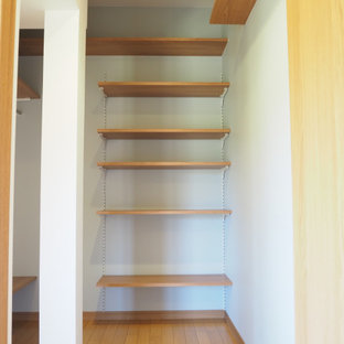 Immagine di armadi e cabine armadio moderni di medie dimensioni con pavimento in compensato, pavimento marrone e soffitto in carta da parati