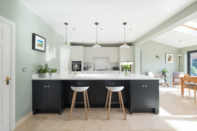 Inspiration for a large classic grey and black single-wall open plan kitchen in Cardiff with an integrated sink, flat-panel cabinets, light wood cabinets, quartz worktops, white splashback, engineered quartz splashback, stainless steel appliances, porcelain flooring, an island, white worktops and feature lighting.