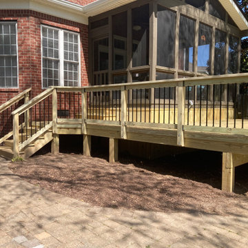 Pressure treated deck w/ black aluminum pickets outside of existing screen room