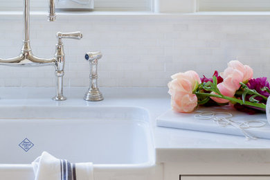 Inspiration for a timeless light wood floor kitchen remodel in San Francisco with a farmhouse sink, white cabinets, marble countertops, white backsplash, mosaic tile backsplash, stainless steel appliances and an island