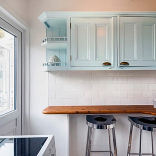 Photo of a small victorian u-shaped kitchen pantry in Dublin with a drop-in sink, beaded inset cabinets, turquoise cabinets, wood benchtops, white splashback, ceramic splashback, white appliances, laminate floors, no island, grey floor and white benchtop.