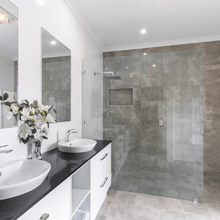Immagine di una grande stanza da bagno padronale moderna con ante a filo, ante bianche, doccia aperta, piastrelle grigie, piastrelle in ceramica, pareti bianche, pavimento con piastrelle in ceramica, lavabo a bacinella, top in granito, pavimento grigio, doccia aperta e top nero
