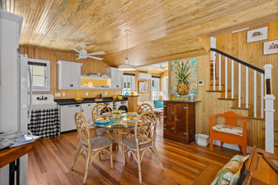 タンパにある小さなビーチスタイルのおしゃれなダイニングキッチン (茶色い壁、濃色無垢フローリング、暖炉なし、茶色い床、板張り天井、板張り壁) の写真