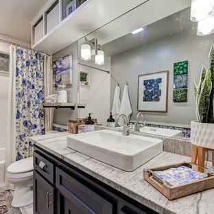 Foto di una stanza da bagno moderna di medie dimensioni con ante in stile shaker, ante blu, vasca ad alcova, vasca/doccia, WC a due pezzi, piastrelle bianche, piastrelle in ceramica, pareti grigie, pavimento con piastrelle in ceramica, lavabo rettangolare, top in granito, pavimento grigio, doccia con tenda e top multicolore
