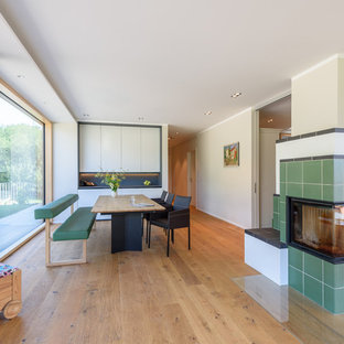 シュトゥットガルトの中サイズのコンテンポラリースタイルのLDKの画像 (ベージュの壁、無垢フローリング、コーナー設置型暖炉、タイルの暖炉まわり、茶色い床)